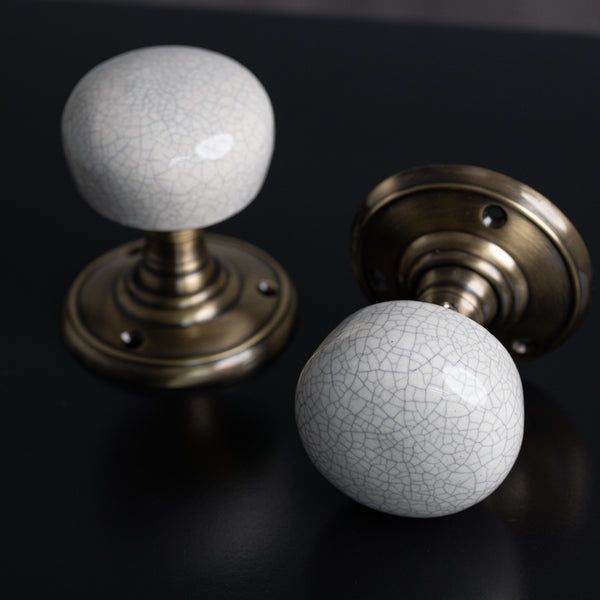 Paire de boutons de porte en porcelaine blanche craquelée et laiton vieilli.